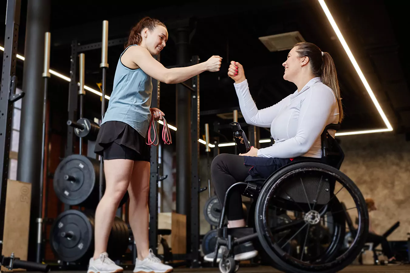A disabled woman in her wheel chair gives a fist bump to her trainer